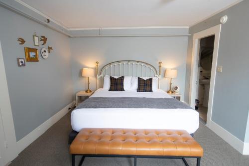 a bedroom with a large bed and a bench at The New London Inn in New London