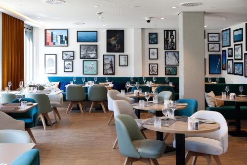 a restaurant with tables and chairs and pictures on the walls at Holiday Inn - Hamburg - HafenCity by IHG in Hamburg