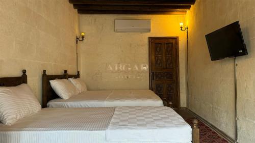 two beds in a room with a tv on the wall at ABGAR Otel in Sanlıurfa