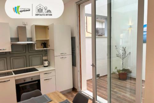 a kitchen with white cabinets and a glass wall at Comacchio Experience - Ospitalità Diffusa in Lido di Pomposa