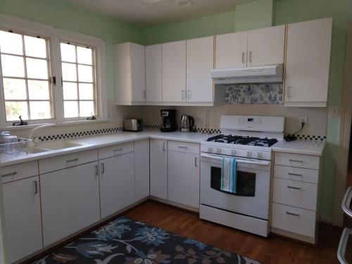 a kitchen with white cabinets and a stove top oven at Charming Classic Cottage 2Br in Durham