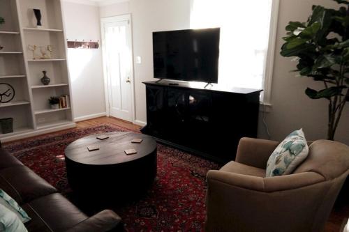 a living room with a tv and two chairs and a coffee table at Charming Classic Cottage 2Br in Durham