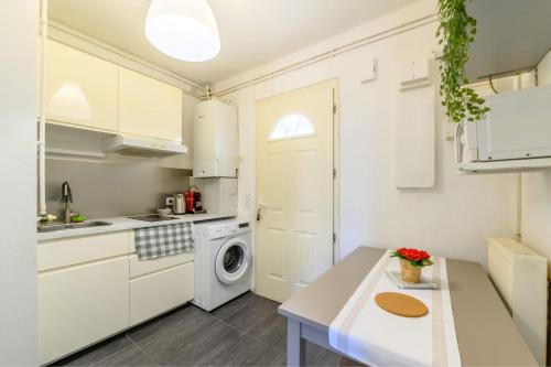 une cuisine avec des armoires blanches et une laveuse et une sécheuse dans l'établissement Le Chevreul appartement entier proche Paris, à Choisy-le-Roi