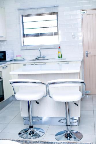 a kitchen with two bar stools in front of a sink at JTown CBD Self-Catering Apartment in Jwaneng