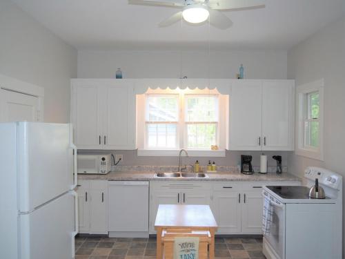 Una cocina con gabinetes blancos y un refrigerador blanco. en Sailor's Delight - Remodeled And Super Cute!, en Manistee