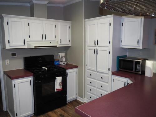 a kitchen with white cabinets and a black stove at The Green Lake Getaway - Shared Lake Access! in Interlochen