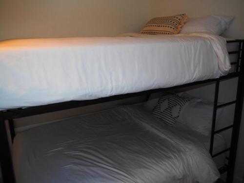 a bunk bed with white sheets and pillows on it at The Bright And Breezy - Lakefront With Spa! in Frankfort