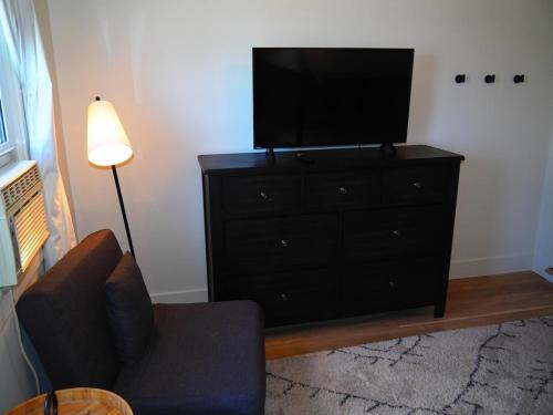 a living room with a black dresser with a flat screen tv at The Bright And Breezy - Lakefront With Spa! in Frankfort