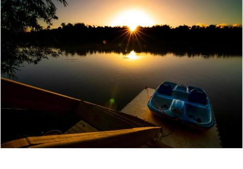 a small boat sitting in the water at sunset at HW Tiny Home in Cidra