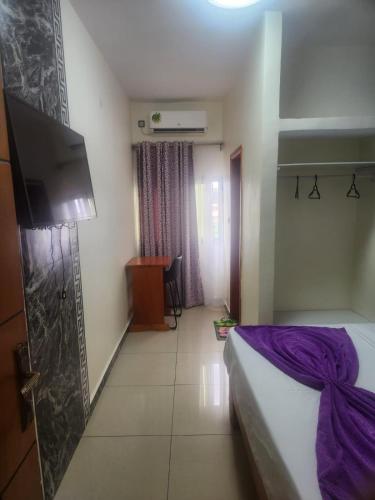 a hotel room with a bed and a flat screen tv at Hôtel SAN PEDRO in Yaoundé