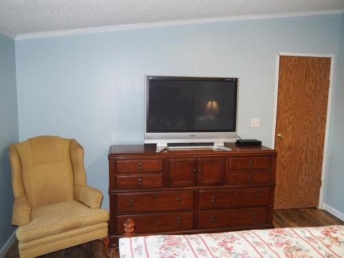 a bedroom with a tv on a dresser and a chair at The Green Lake Getaway - Shared Lake Access! in Interlochen