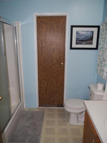 a bathroom with a toilet and a wooden door at The Green Lake Getaway - Shared Lake Access! in Interlochen