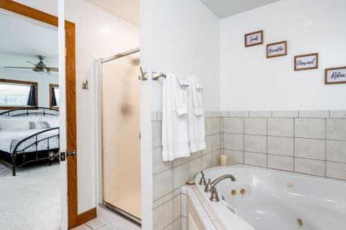a white bathroom with a tub and a bedroom at Sunset Bay - Lakefront, Large, And Gorgeous! in Frankfort