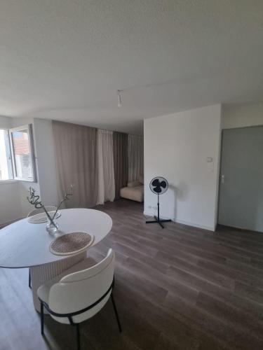 un salon avec une table et des chaises blanches dans l'établissement Appartement au centre ville d'Avignon, à Avignon