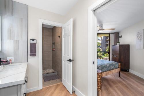 a bathroom with a bed and a walk in shower at Hip Hawaiian Oceanfront Vistas in Kihei