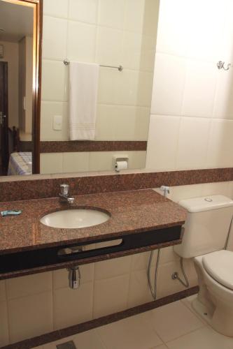 a bathroom with a sink and a toilet and a mirror at Hotel São Bento in Belo Horizonte