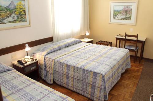 a hotel room with two beds and a table at Hotel São Bento in Belo Horizonte