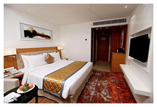 a hotel room with a large bed and a television at Best Western Plus Tejvivaan in Visakhapatnam
