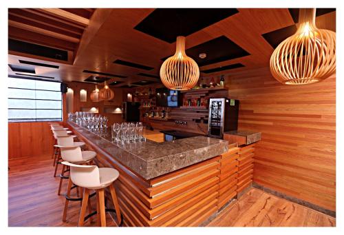 a bar with a row of bar stools and lights at Best Western Plus Tejvivaan in Visakhapatnam