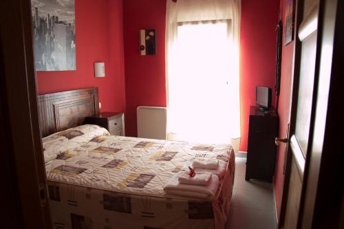 a bedroom with a bed with red walls and a window at Apartahotel Rural CollaRubio Luxury in Collado Mediano