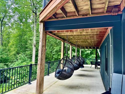 Un porche cubierto con un edificio azul con columpios. en MOONLIGHT MOUNTAIN MANOR - Cedar Hot Tub, Views & Games, en Horse Shoe