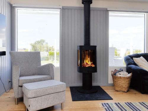 a living room with a fireplace and a chair at 6 person holiday home in Karrebæksminde-By Traum in Karrebæksminde