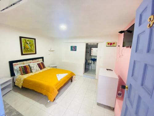 a bedroom with a bed with a yellow blanket at House Marfito Airport in Cartagena de Indias