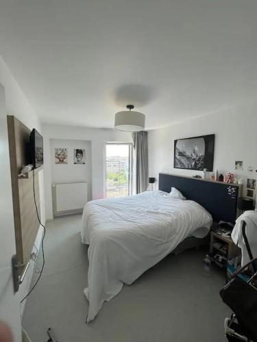 une chambre blanche avec un lit et une fenêtre dans l'établissement Appartement - Batignolles Paris, à Paris