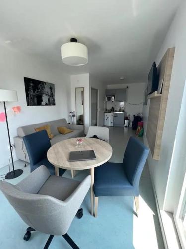 un salon avec une table et des chaises bleues dans l'établissement Appartement - Batignolles Paris, à Paris