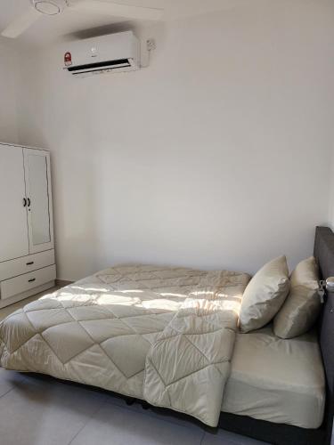 a bed in a bedroom with a white wall at Homestay Warisan Iman in Klang