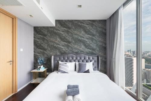 a bedroom with a large bed and a large window at The Echelon Sukhumvit 11 by LeFoyer in Bangkok