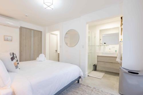 a white bedroom with a white bed and a bathroom at Charming & Spacious 2BR Condo E22 at Playa Venao in Playa Venao