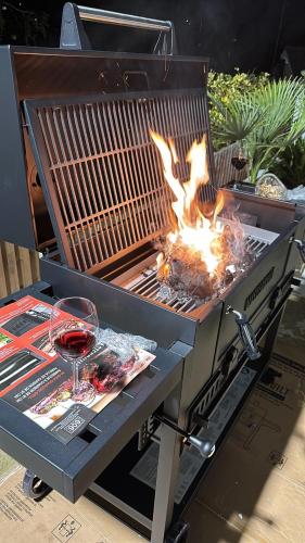 a barbecue grill with a glass of wine and fire at Luxurious & Elegant 6-Bed House in Barnet
