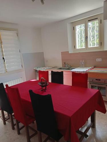une table rouge dans une cuisine avec un tissu de table rouge dans l'établissement La garenne basse chez Sylvie, à Saint-Didier