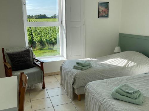 une chambre avec deux lits et une chaise et une fenêtre dans l'établissement Gîte de caractère au cœur des vignes avec jardin, vélos et équipements bébé - FR-1-306-796, à Châteauthébaud