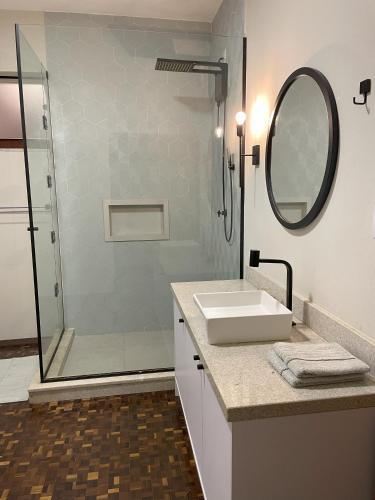 a bathroom with a sink and a shower with a mirror at Apartamento tropical no centro de Pomerode in Pomerode
