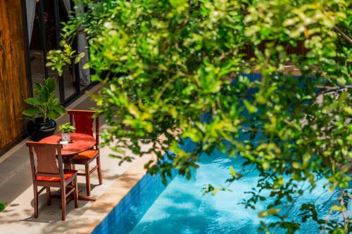 a table and chairs sitting next to a swimming pool at Tiny Home in Phumi Ta Phul