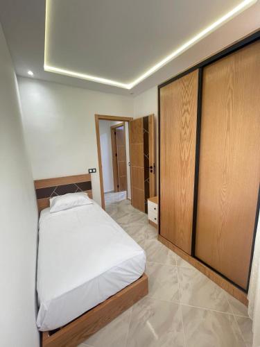 a bedroom with a white bed and wooden cabinets at Alquds اقامة القدس in Fnidek
