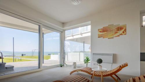 a living room with a table and a view of the ocean at Infinity Apartman Lellemarine in Balatonlelle