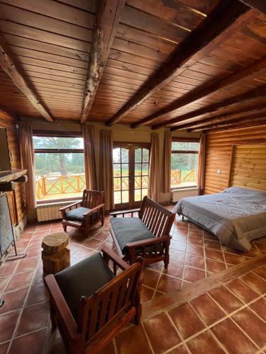 a bedroom with a bed and two chairs and windows at La Margarita in El Bolsón