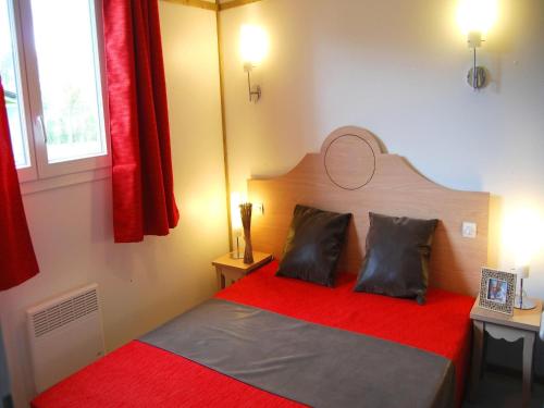 une chambre avec un lit rouge avec deux oreillers dans l'établissement Chalet in France with Garden Terrace, à Castelmoron-sur-Lot