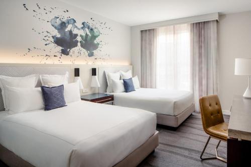 a hotel room with two beds and a desk at Archer Hotel Old Town Alexandria in Alexandria
