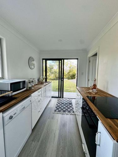 a kitchen with white appliances and a large window at Hinterland Heights in Canungra