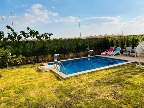 a swimming pool in a yard with two chairs at اكتوبر الشيخ زايد بجوار مول العرب in Sheikh Zayed
