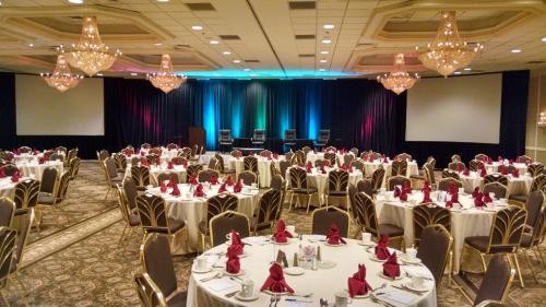 a banquet hall with white tables and chairs and chandeliers at Clayton Plaza Hotel & Extended Stay in Clayton