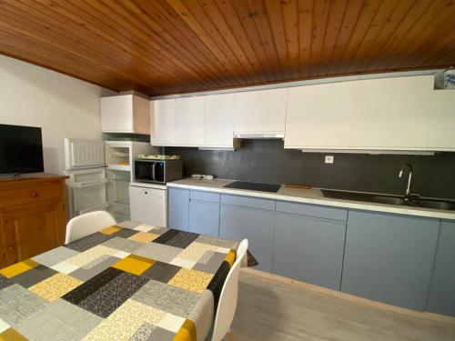 une cuisine avec une table et des placards blancs dans l'établissement Appartement à 150m de la plage, centre-ville, parking privé, équipé tout confort - FR-1-22-297, à La Tranche-sur-Mer