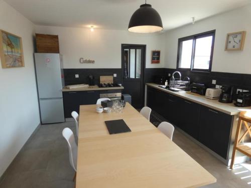 une cuisine avec une table en bois avec des chaises et un comptoir dans l'établissement Maison spacieuse avec jardin clos, près plage, animaux OK, 10 pers, Notre-Dame-de-Monts - FR-1-540-137, à Notre-Dame-de-Monts