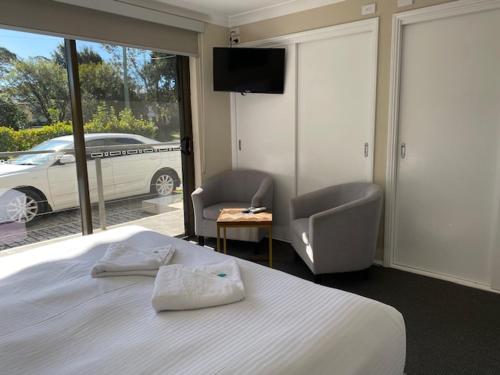 a bedroom with a bed and a television and a car at Huskisson Beach Escape in Huskisson