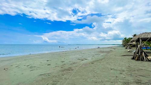 a beach with a straw hut and the ocean at Cabaña Villa Palmaral in Moñitos