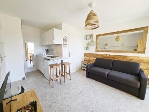 un salon avec un canapé et une cuisine dans l'établissement Studio refait en 2024 avec terrasse, climatisation et parking, à 50m de la plage - FR-1-338-588, à Sète